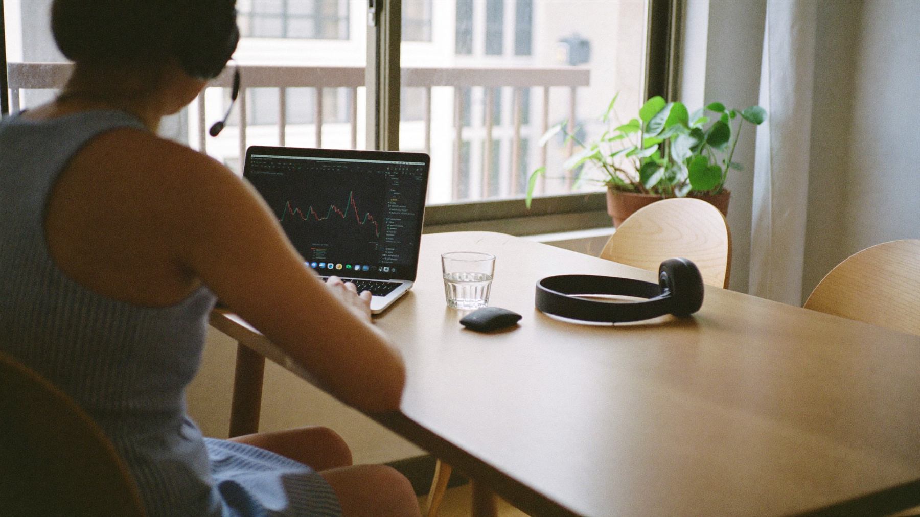An assistant with a headset working at a laptop on a bright dining table